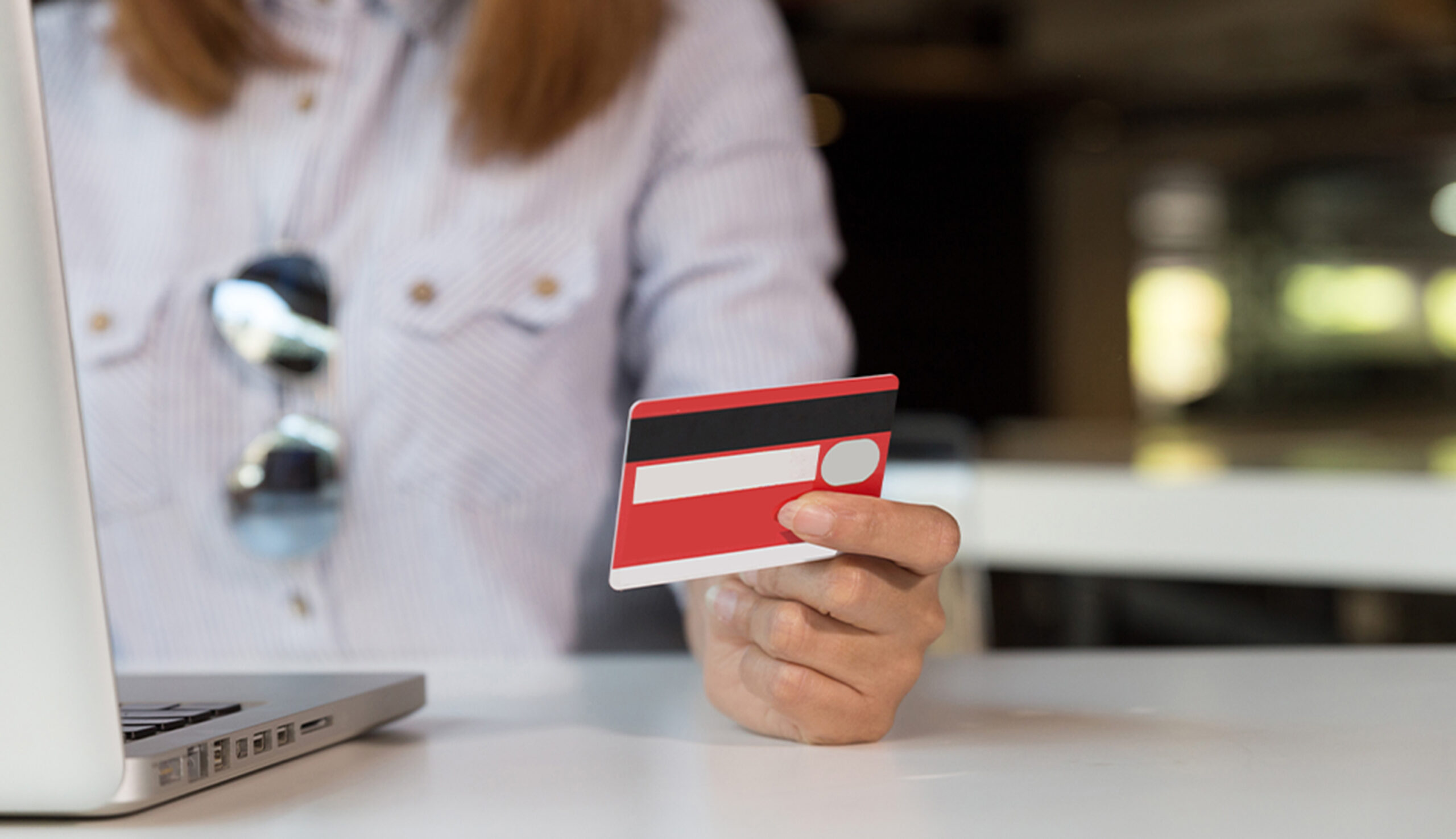 Woman's hands holding a credit card and using a laptop computer.