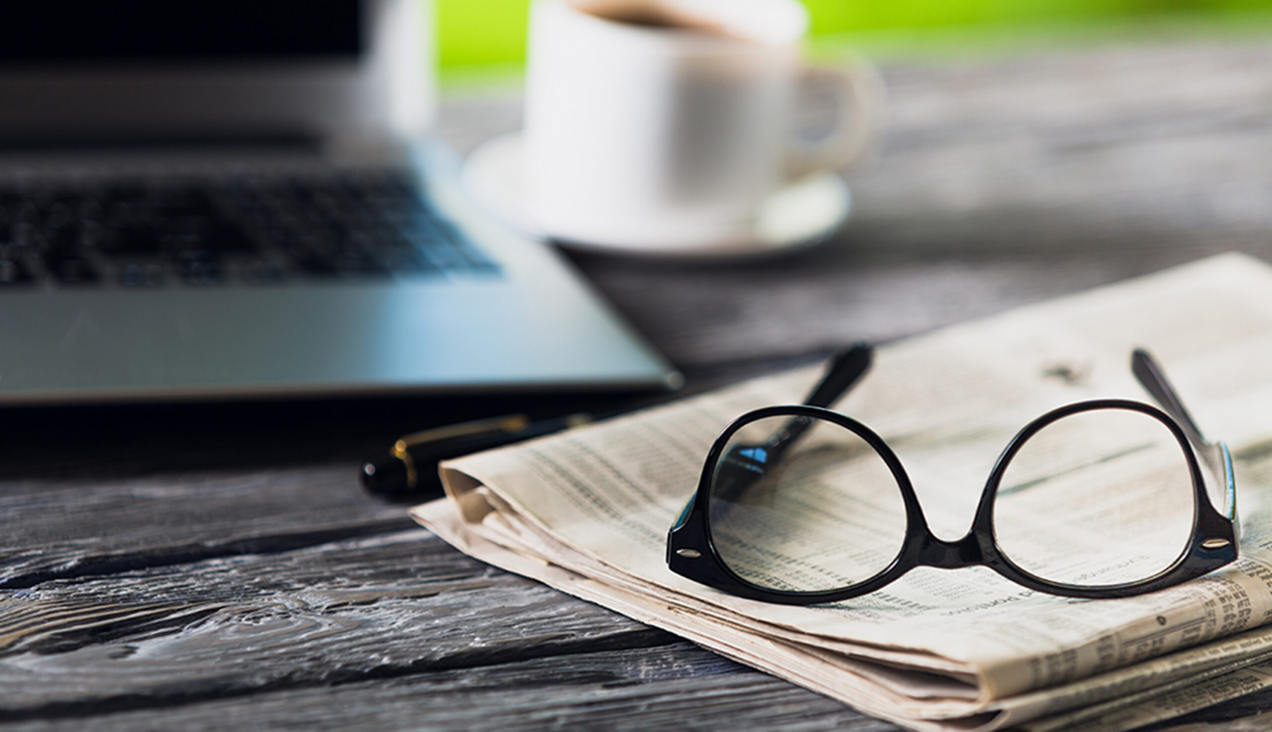 Newspaper with computer on table.